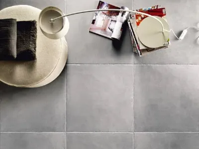 lampada e pouf su pavimento grigio